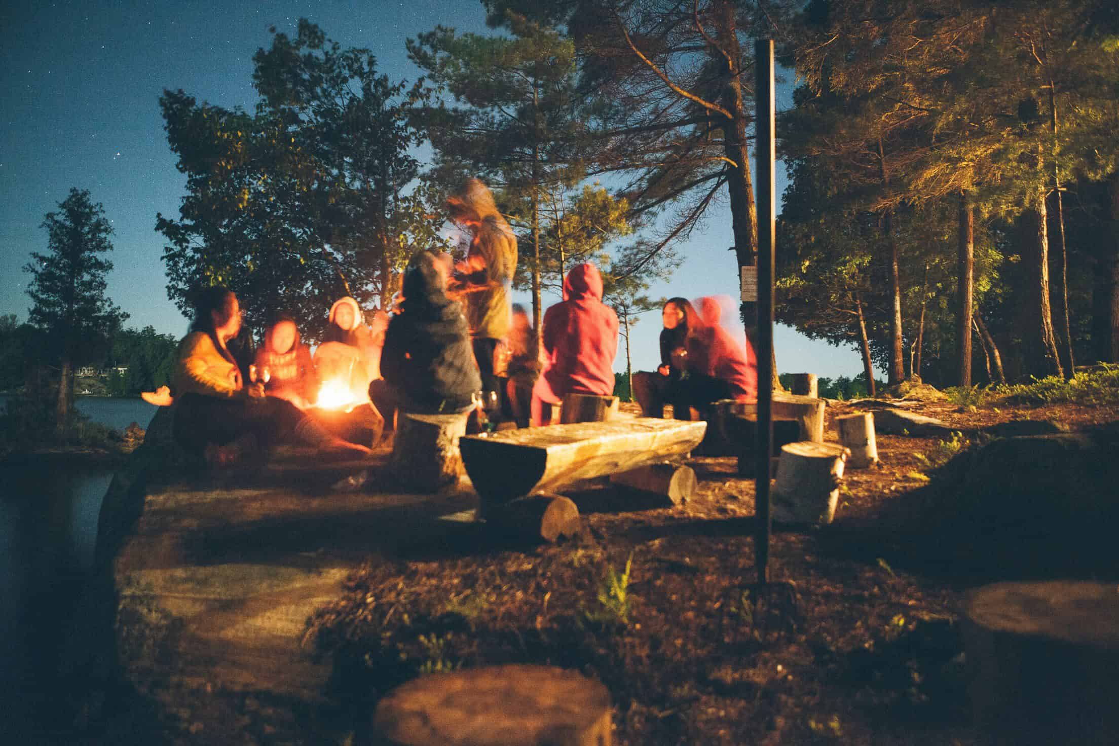 group of people sitting around the bonfire