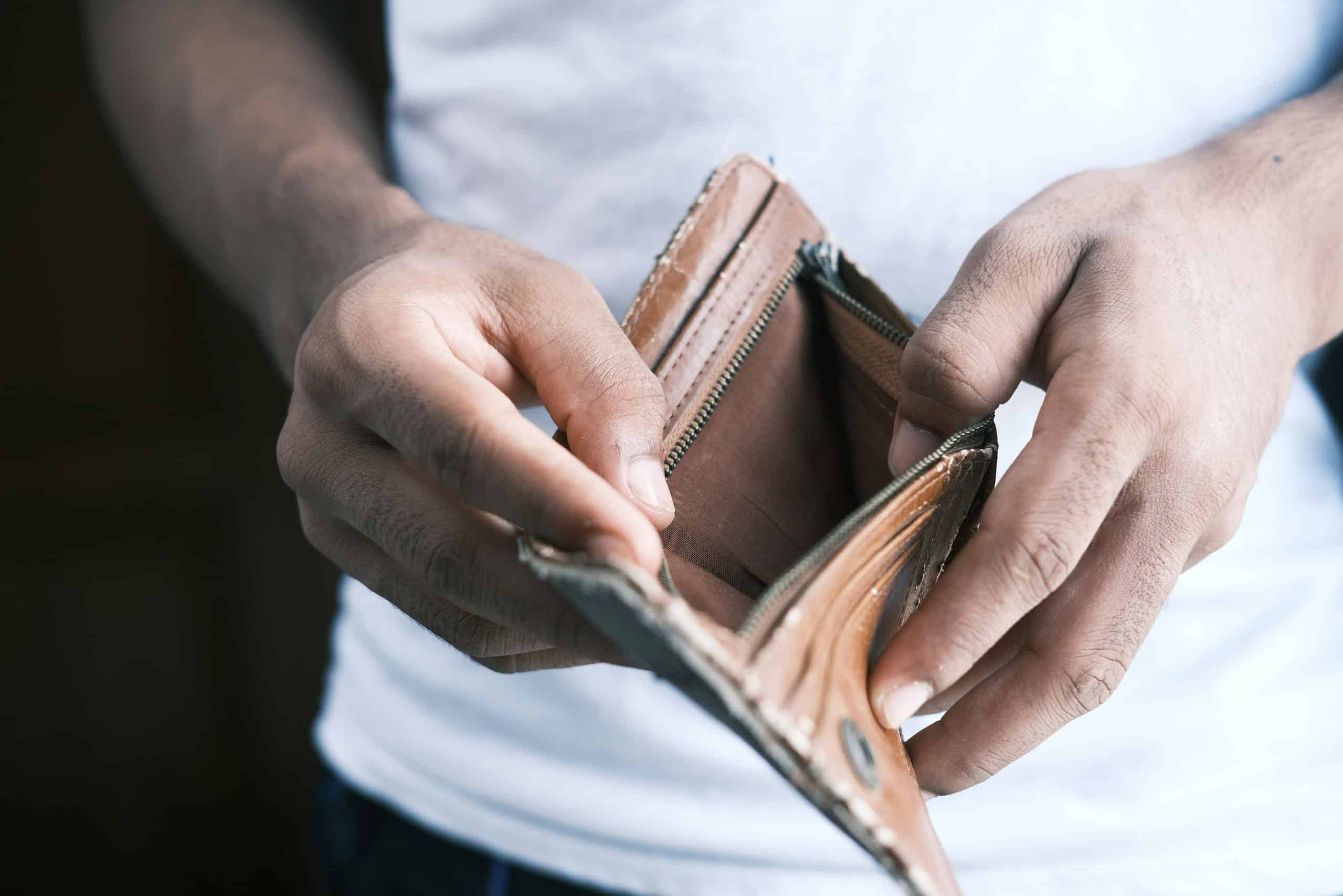 a man opening an empty brown leather wallet