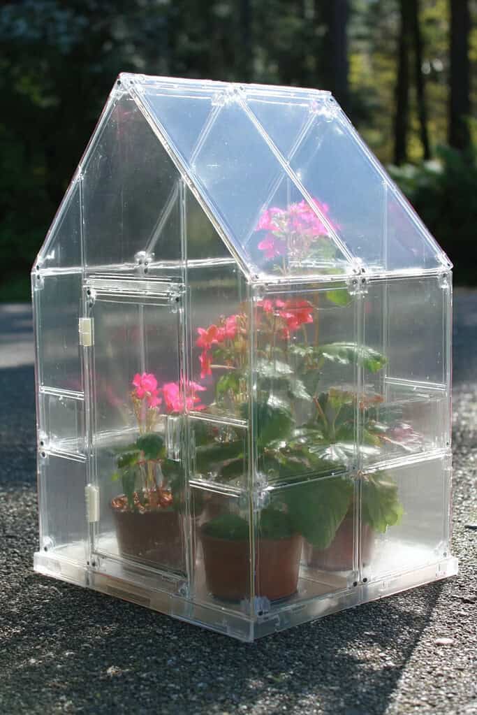 a small, DIY tabletop greenhouse built entirely from repurposed clear plastic CD jewel cases. 
