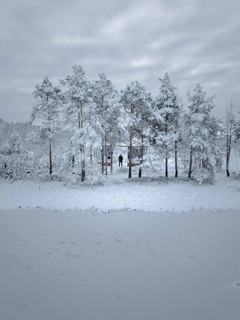 Man navigating through deep snow with a backpack and trekking poles
