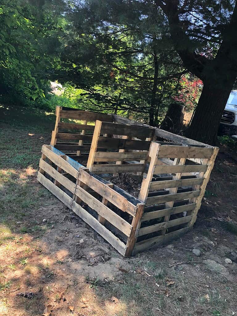 a rustic outdoor compost bin made from upcycled wooden pallets