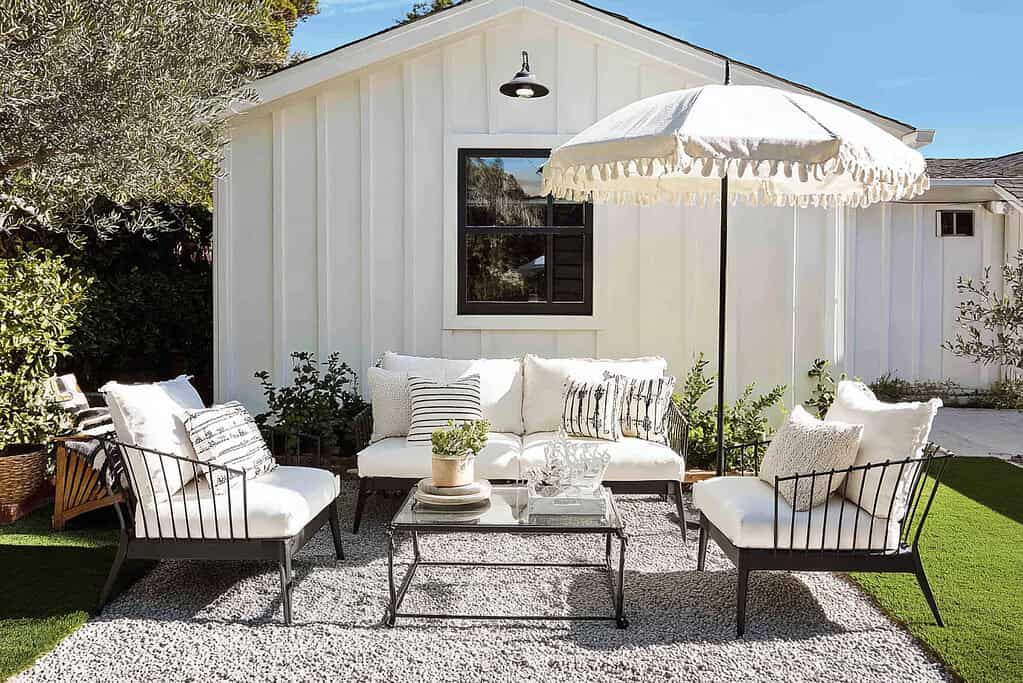a bright and modern backyard lounge area set against a crisp white board-and-batten cottage-style house
