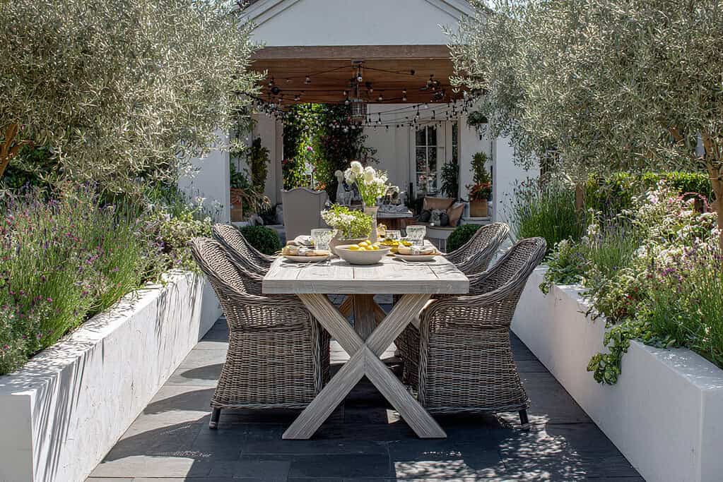 a luxurious and lush garden dining area nestled between tall white raised flower beds