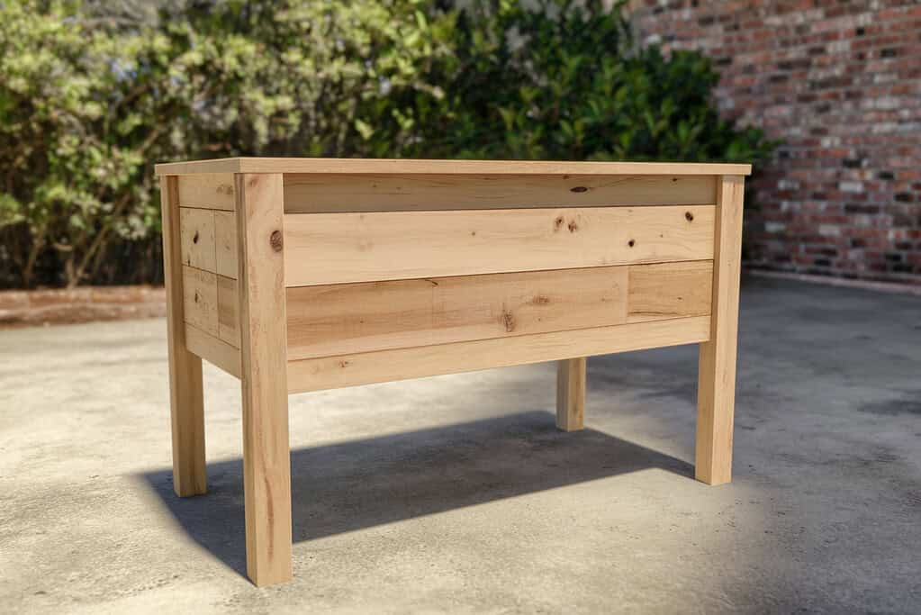 a handcrafted elevated wooden planter box standing on a concrete patio.