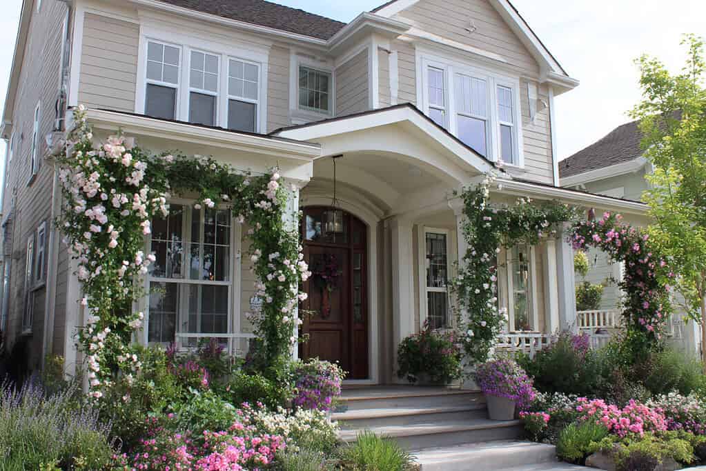 a charming home--cottage, farmhouse, or traditional suburban style--featuring vertical garden accents with flowering vines climbing up structures in the front yard