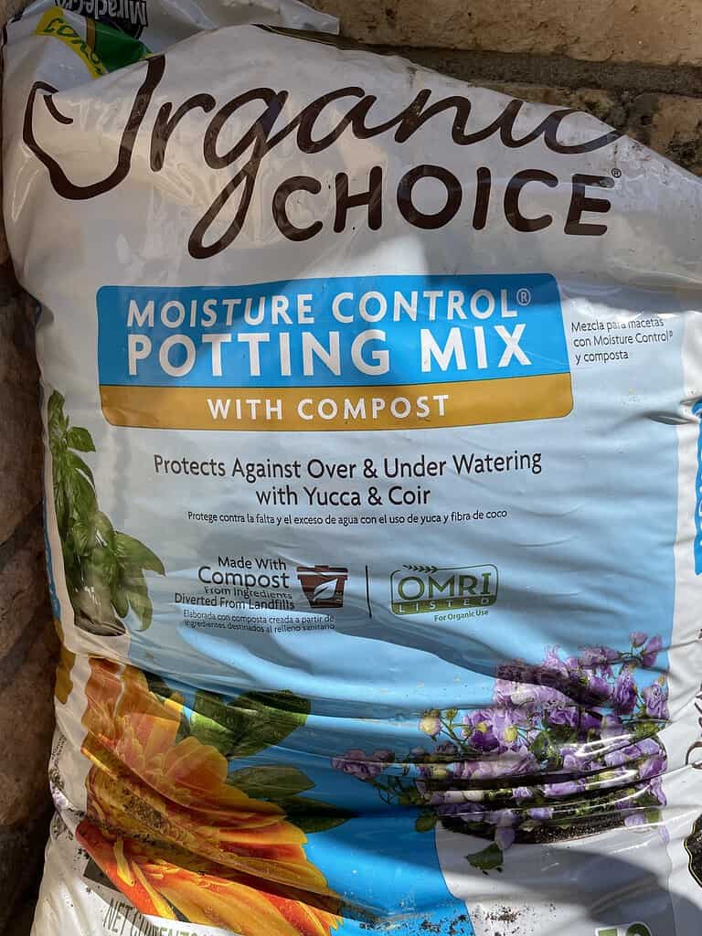 an organic gardening setup showcasing a large bag of "Organic Choice Moisture Control Potting Mix with Compost."