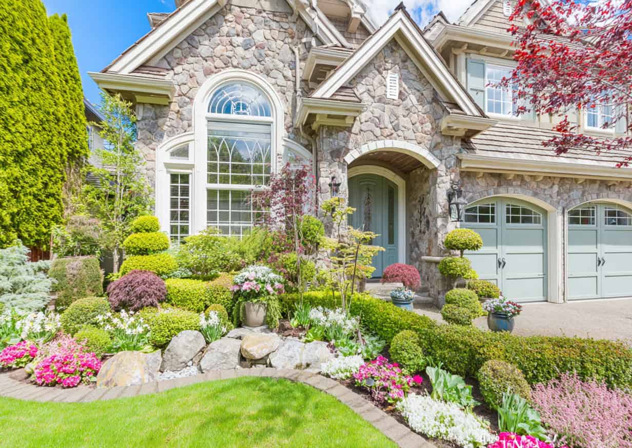 a luxurious, professionally landscaped suburban home in full spring or early summer bloom.