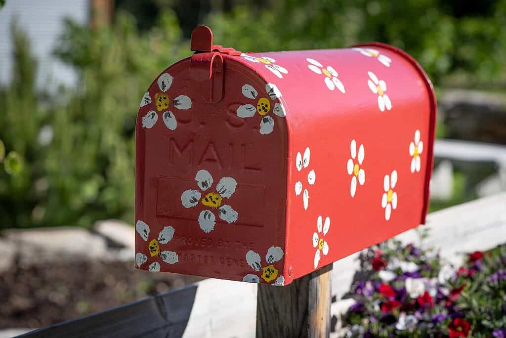 a classic red metal mailbox mounted on a natural wooden post