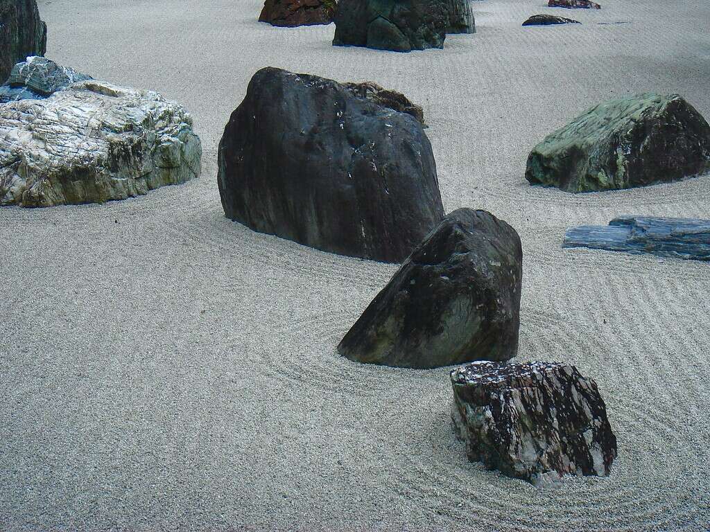 Zen-inspired rock garden with large decorative boulders arranged in raked gravel sand