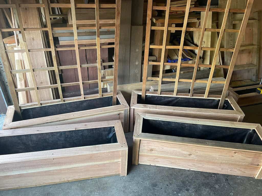 handcrafted wooden planter boxes with attached lattice trellises, arranged inside a rustic woodworking shed