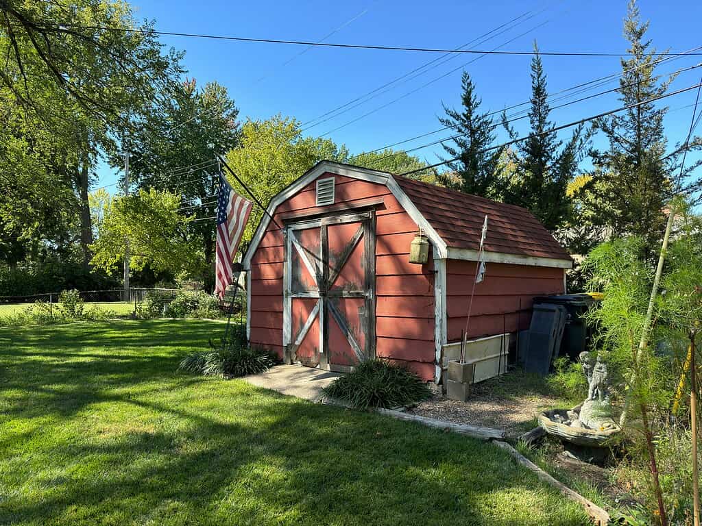 a small rustic red garden shed in a quiet suburban backyard