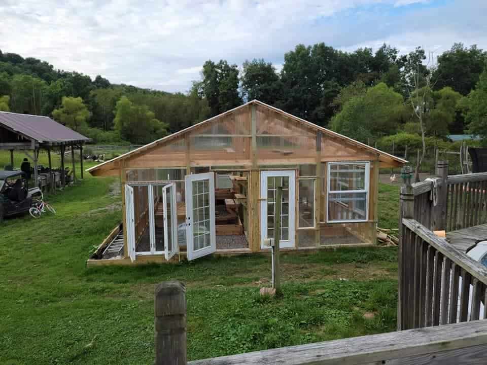 a handcrafted wooden greenhouse shed set in a lush rural landscape.