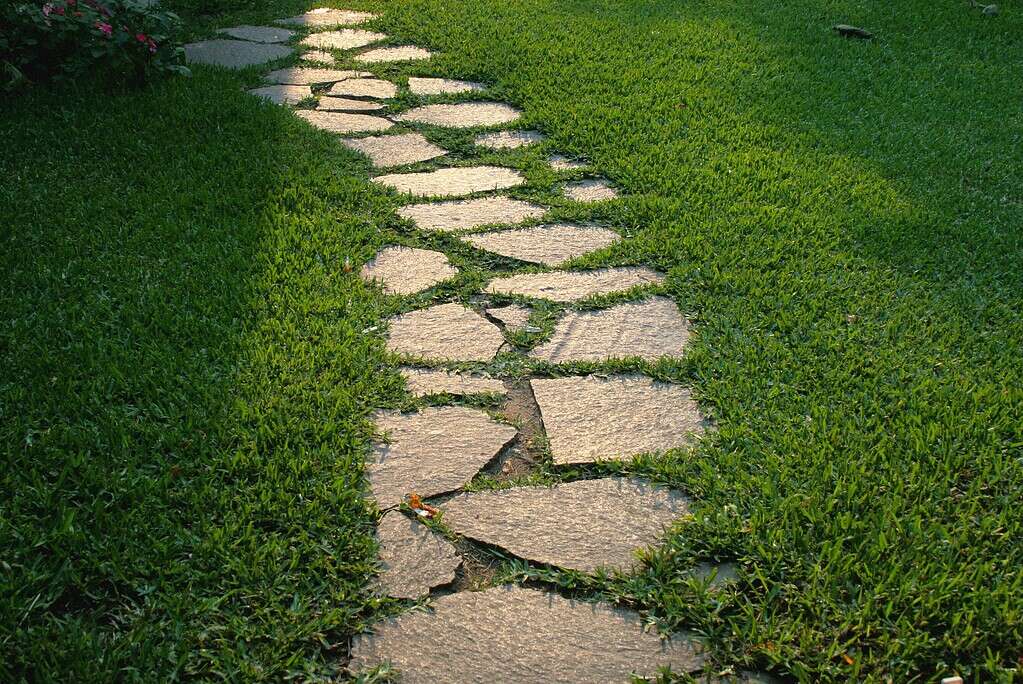 Natural stone stepping path set into green lawn grass