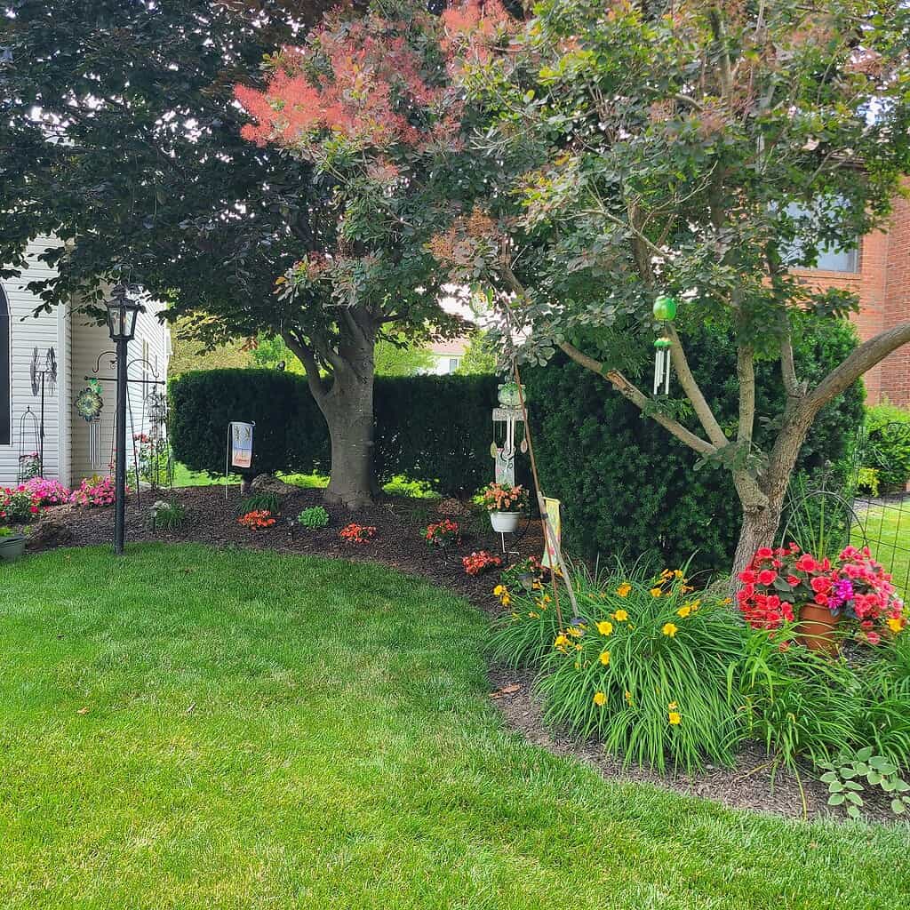 front yard landscaping with mature tree and flower bed border