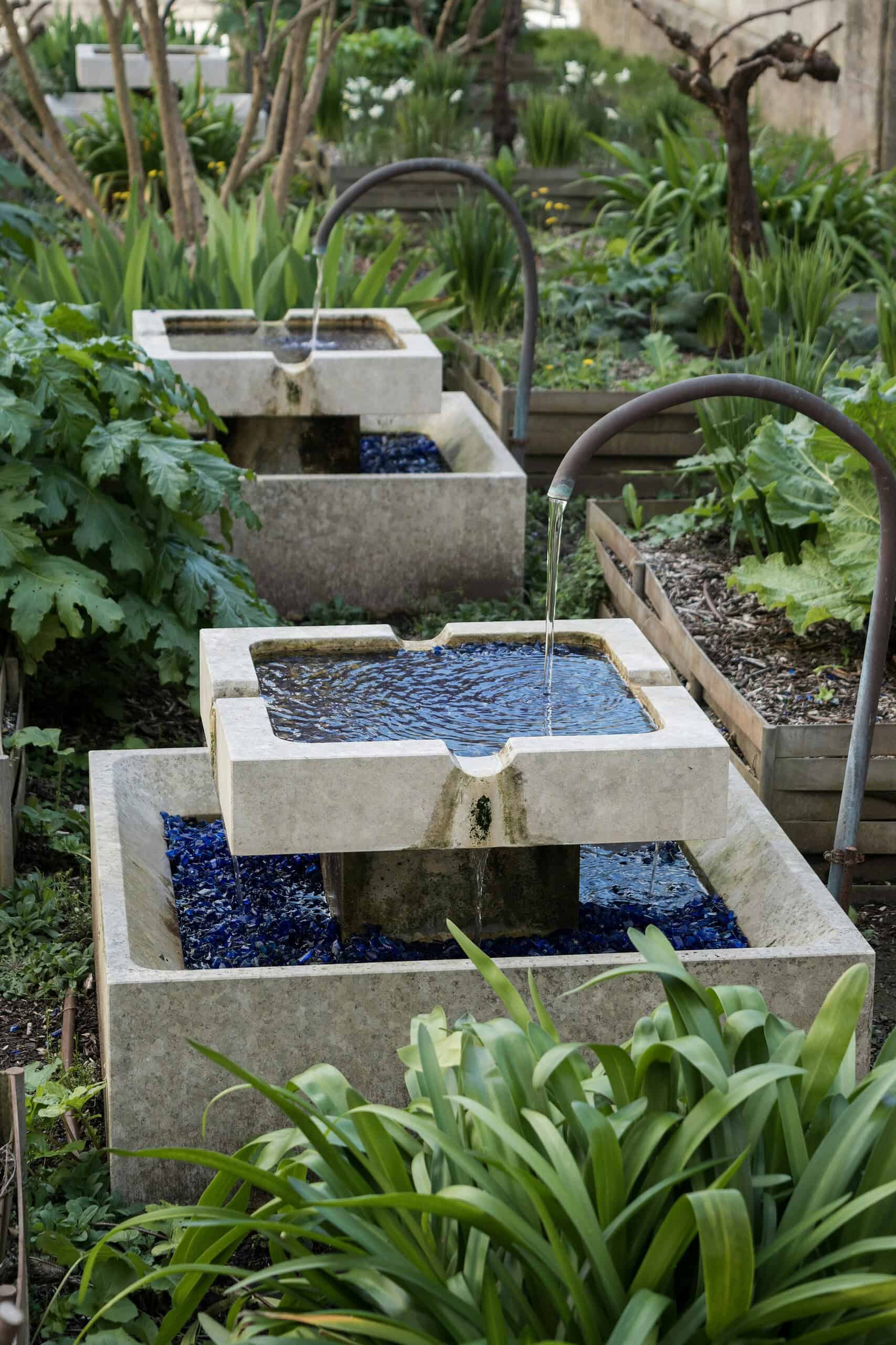 DIY solar water fountain with stone basins in a garden.