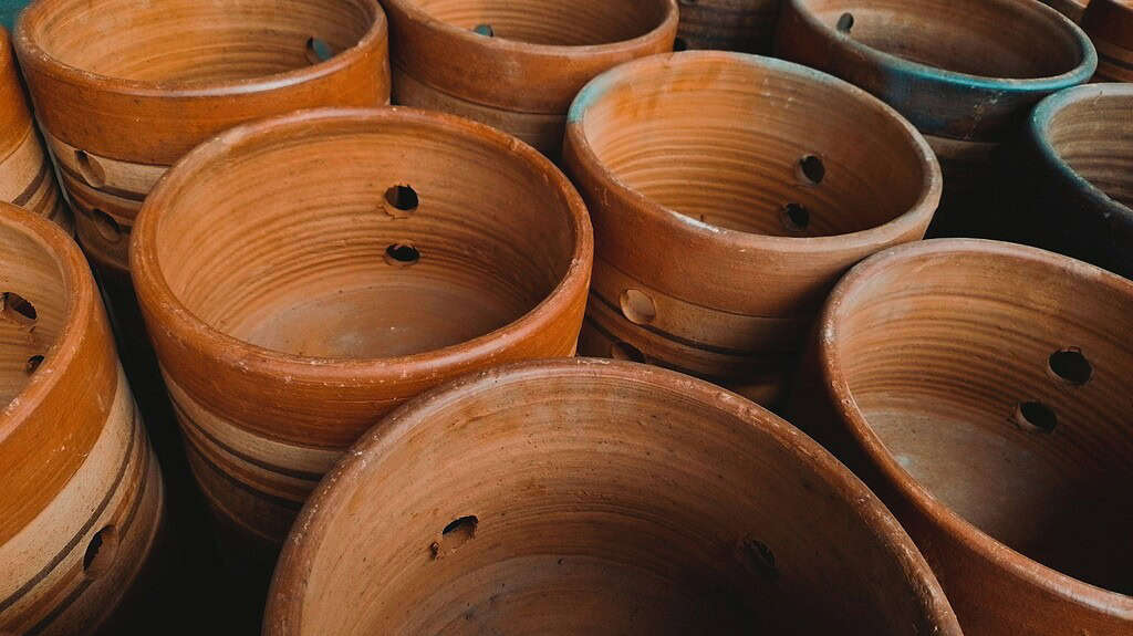 Stacked terracotta garden pots with visible drainage holes, showing natural clay texture and warm earthy tones.