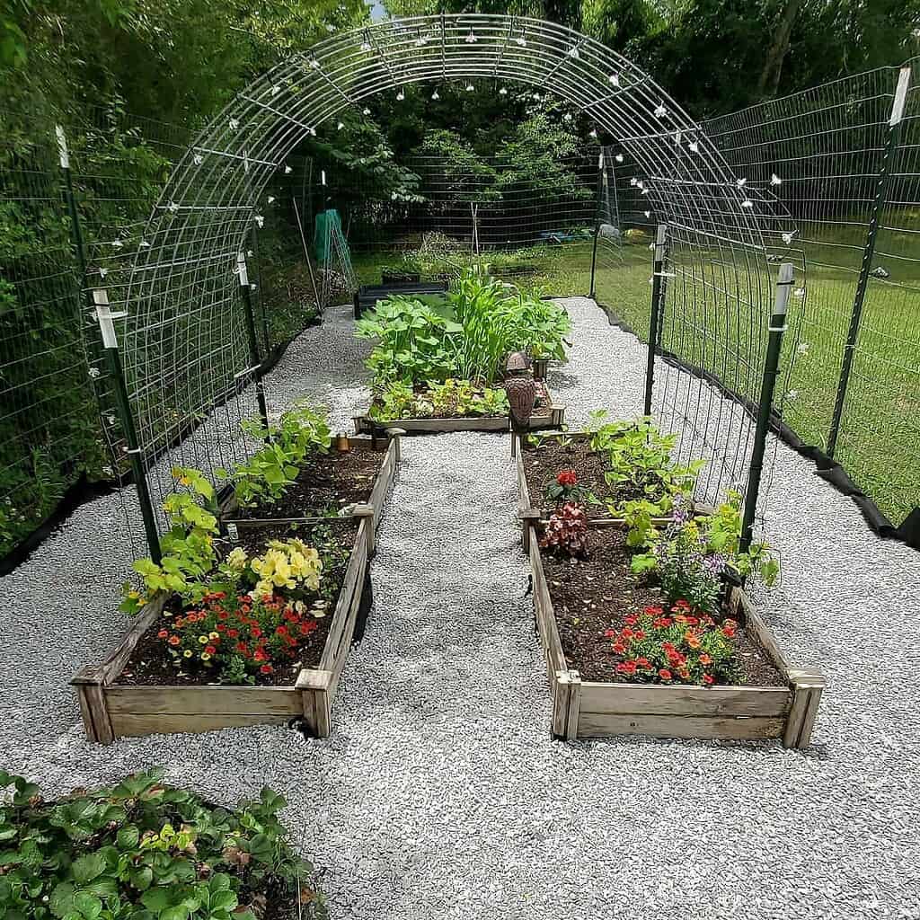 Arched garden trellis tunnel over raised beds with gravel path in backyard garden