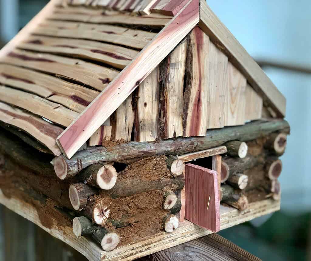Rustic DIY birdhouse made from natural wood and branches with log cabin design