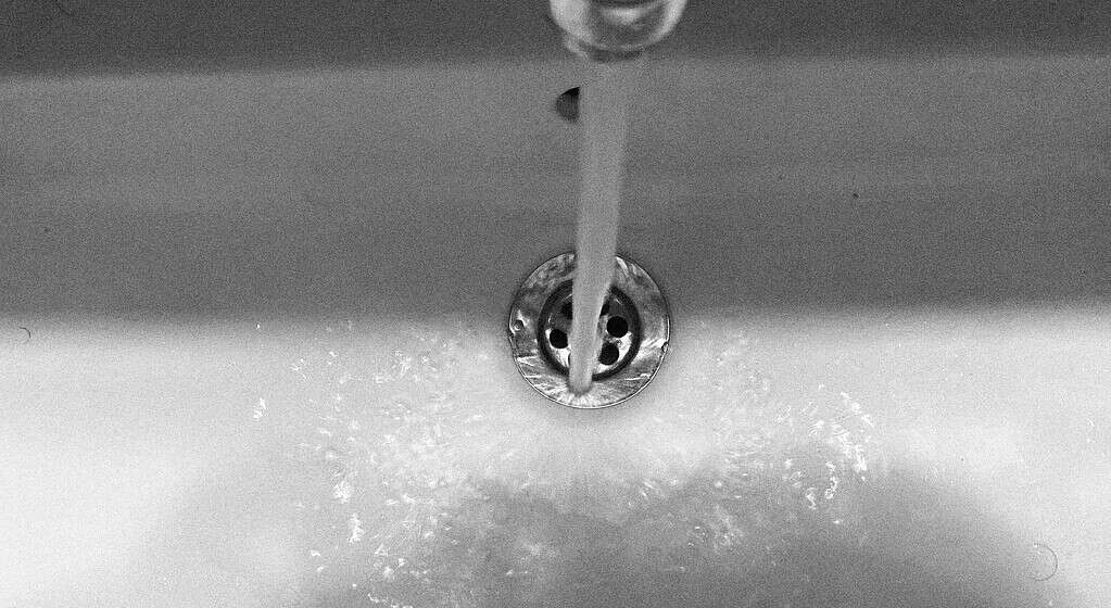 Water flowing from a faucet into a sink drain.