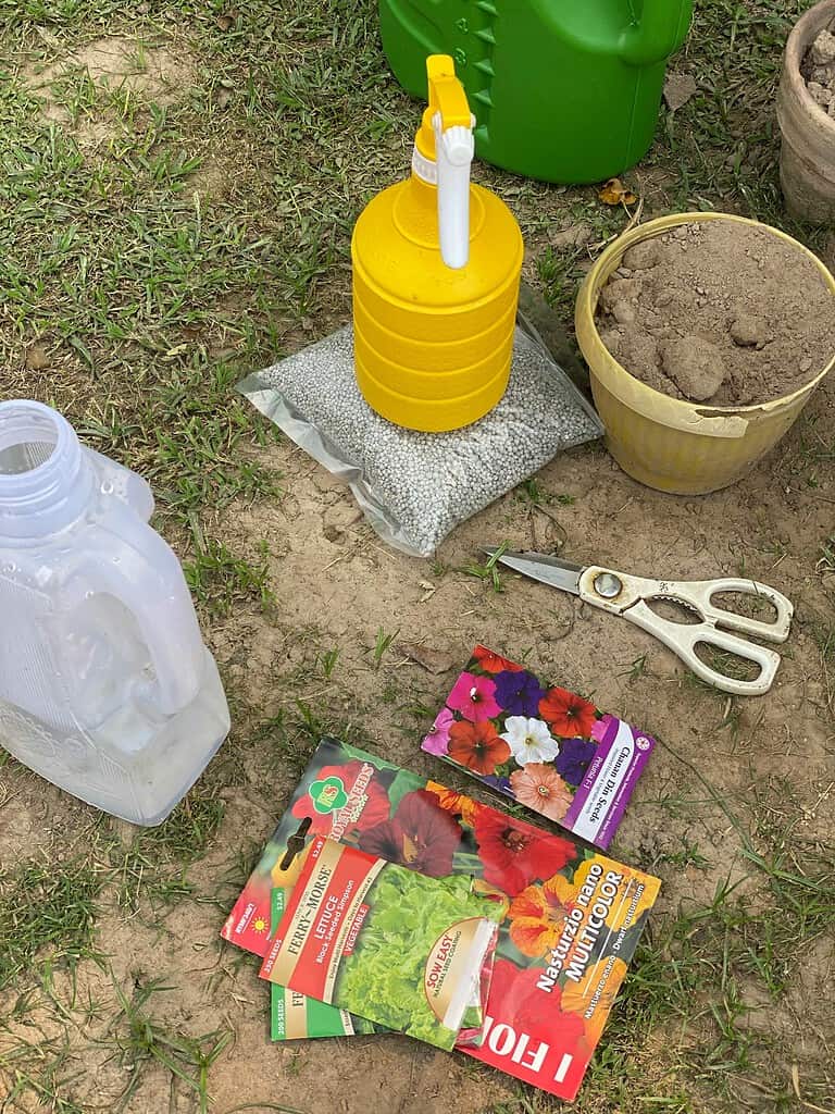 Gardening supplies on the ground, including seed packets, scissors, soil, and watering containers.
