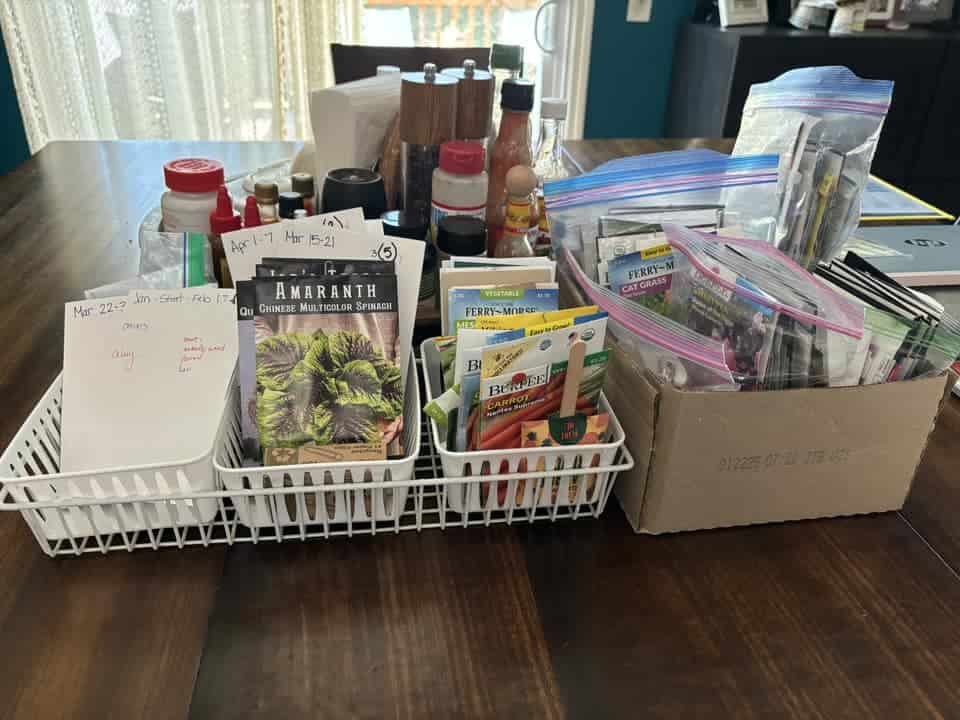 Organized seed packets and gardening supplies on a table with notes and containers.
