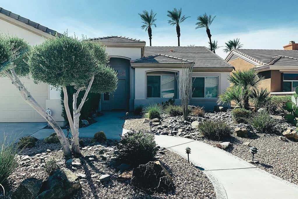 River rock landscaping in front yard with desert plants, gravel beds, and curved walkway.

