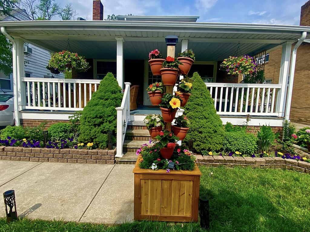 Flower pots stacked vertically with colorful blooms in a front yard garden display.