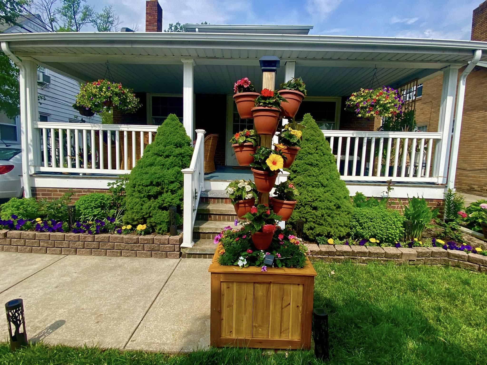 Flower pots stacked vertically with colorful blooms in a front yard garden display.